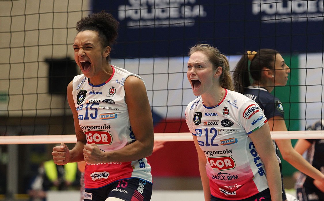 Two women's volleyball players cheer for their teamamtes