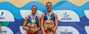 Two female beach athletes with medals and flowers