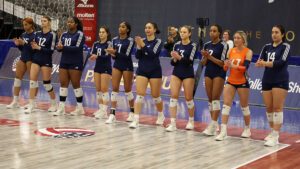 Girls volleyball players stand at the side of a court before a match