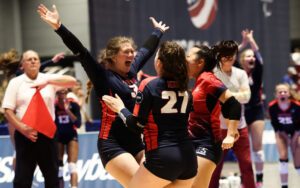 A player with her arms raised goes to celebrate a teammate