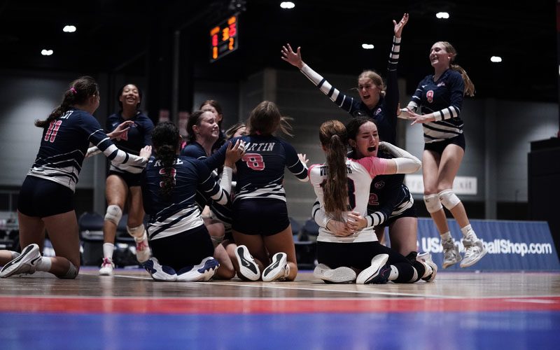 A group of girls volleyball players hugging on the court