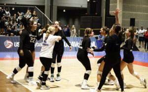 A group of girls standing on the court celebrating