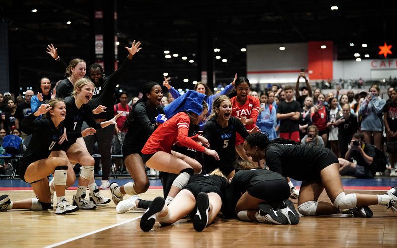 A group of girls huddle on the court in celebration