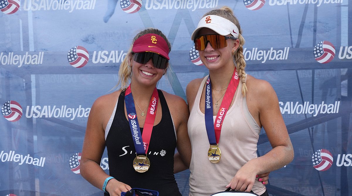 Two girls in visors and sunglasses wear their medals as they are 18 Open champs at Beach Nationals