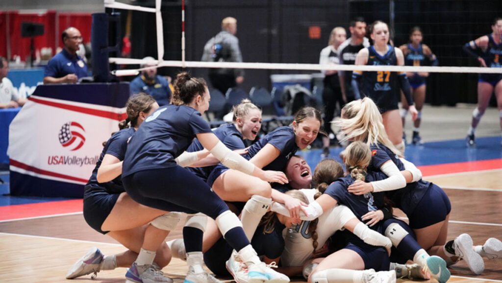 A group of girls dogpile on the court