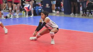 A girl on the indoor court reaches down for a pass