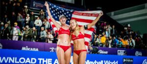 Kelly Cheng and Sara Hughes hold up the American flag on the sand