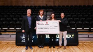 Four people hold a large check