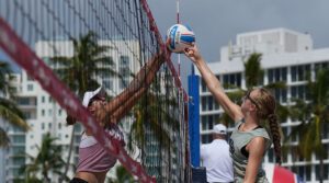 Two athletes joust at the net for control of the ball.
