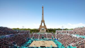 A computer-generated image of a beach volleyball arena sitting in front of the Eiffel Tower.