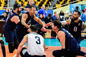 Members of the U.S. Men's Sitting National Team smile and slap hands.