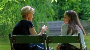 A woman and girl have a discussion on a park bench