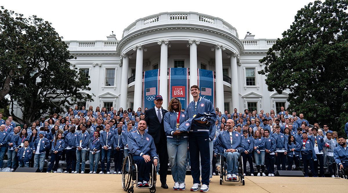 Sitting Volleyball player Nicky Nieves stands next to President Joe Biden as Olympians and Paralympians stand in front of the White House. Photo by Kent Nishimura for Getty Images