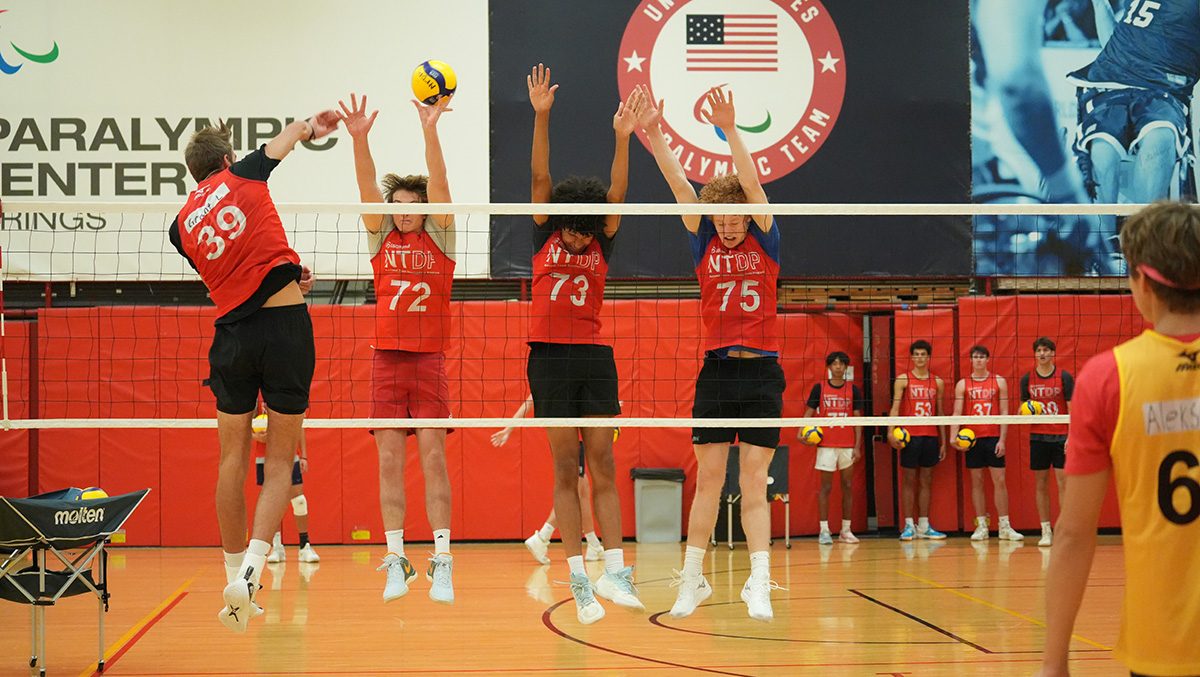 A boys athlete goes up for a hit against the triple block