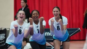 Three girls raise their fists to celebrate on the court