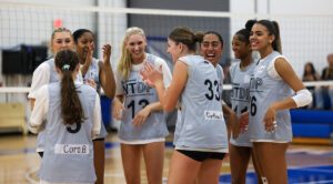 A group of girls athletes celebrate and laugh on the court at an NTDP Training Series