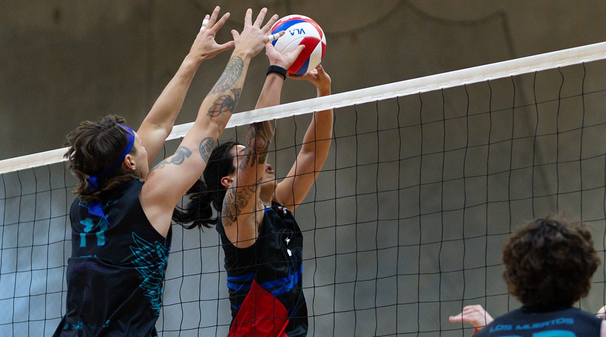 A men's player sets while an opponent is up for the block