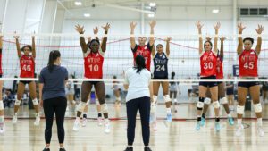 girls volleyball players line up at the net to practice blocking