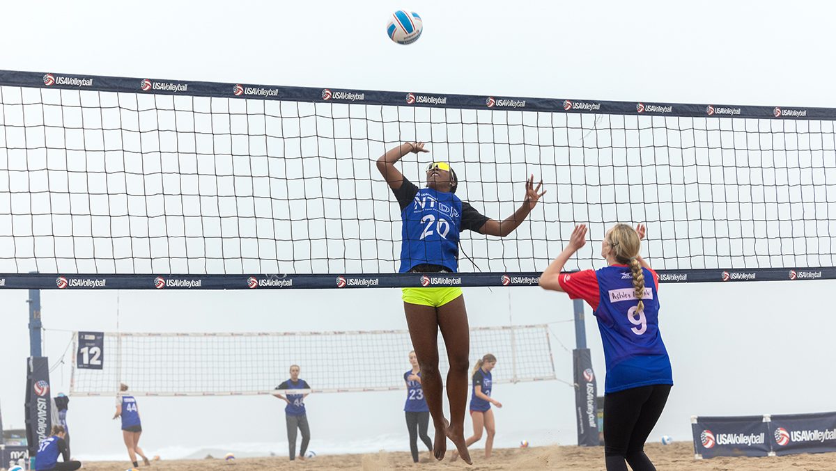 A girls athlete goes up for an attack on the beach