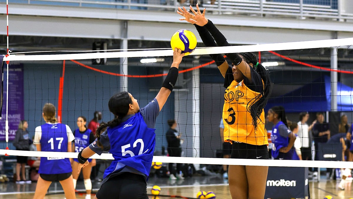 A girls athlete goes up for a block against a player