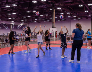 A group of kids on the court learning volleyball